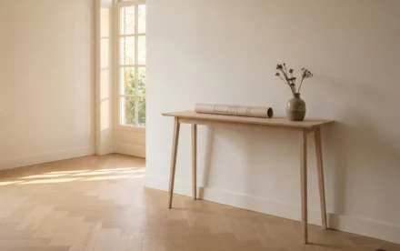 Zonnige Nederlandse hal met licht eiken visgraatparket, architecturaal bestemmingsdocument op smal consoletafeltje naast keramieken vaas.