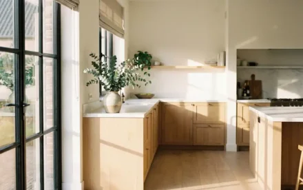 Zonnige Nederlandse keuken met lichte eiken kasten, witte marmeren werkbladen en keramische vaas met eucalyptus in ochtendlicht.