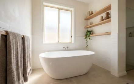 Vrijstaand wit bad in lichte Nederlandse badkamer met eiken houten planken, witte metrotegels en natuurlijk daglicht.